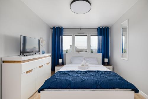 1 dormitorio con 1 cama, TV y cortinas azules en Flaminga Two-Level Apartment, en Szczecin