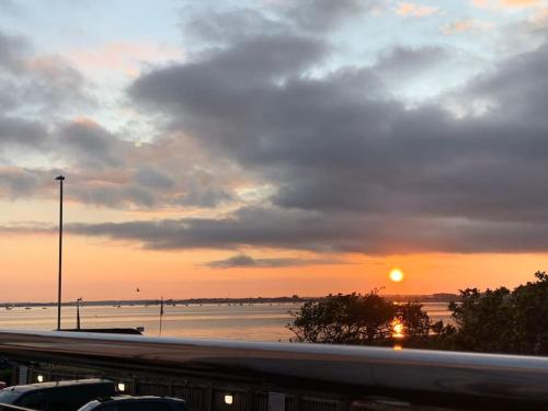 a sunset over a body of water and a freeway at SHOREBANKS - Harbour View Apartment in Sandbanks. in Sandbanks