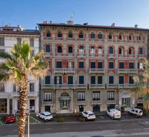 un grand bâtiment avec des voitures garées devant dans l'établissement Hotel Residence Esplanade, à Viareggio