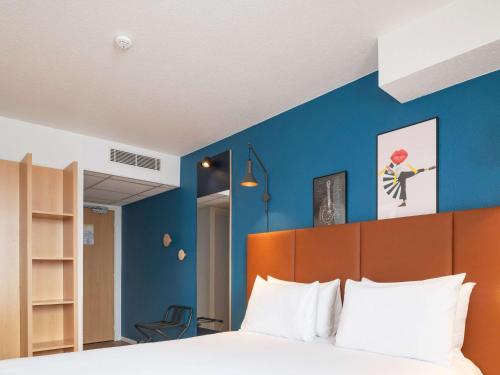 1 dormitorio con 1 cama con pared azul en ibis Bayeux Port En Bessin en Port-en-Bessin-Huppain
