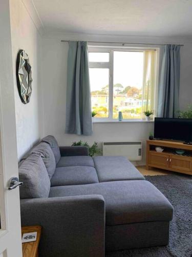 a living room with a couch and a television at SHOREBANKS - Harbour View Apartment in Sandbanks. in Sandbanks