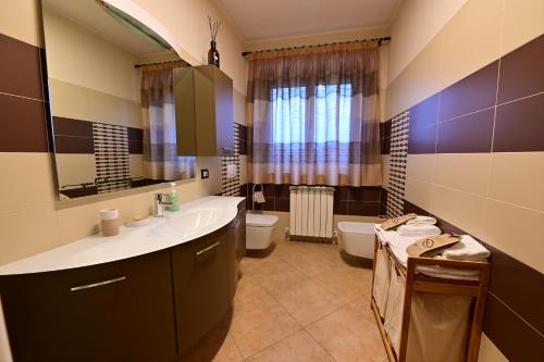 a bathroom with a sink and a toilet and a mirror at Vacancuore, a casa di Giada in Bastia Umbra