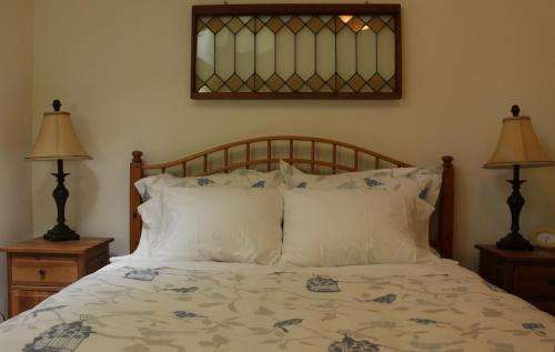 a bedroom with a bed with two lamps and a mirror at Thistle Dew Cottage in Ganges