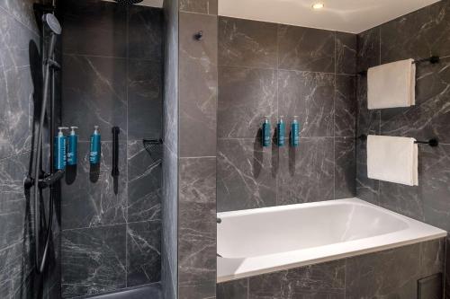 a bathroom with a shower with a white tub at Hilton Paris La Défense in Puteaux