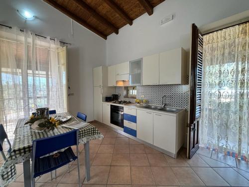 uma cozinha com armários brancos e uma mesa em Rifugio Giudeo em Balestrate
