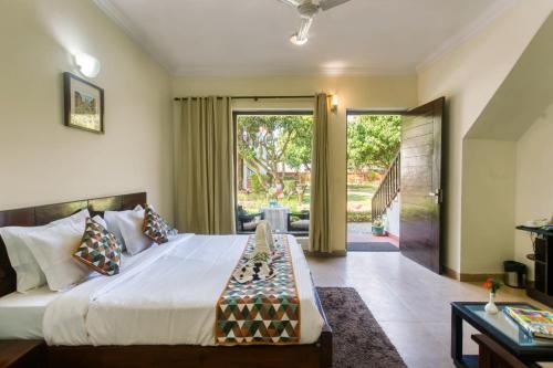 een slaapkamer met een groot bed en glazen schuifdeuren bij Hridey Retreat Resort in Rāmnagar