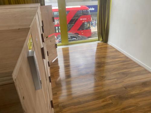 a room with a wooden floor and a red bus at Smart Luggage Store in London