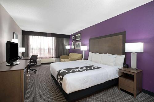 a hotel room with a large bed and a purple wall at La Quinta by Wyndham Rancho Cordova Sacramento in Rancho Cordova