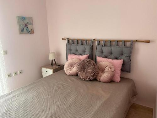 Un dormitorio con una cama con almohadas rosas. en Villa Platania en Palaiokómi