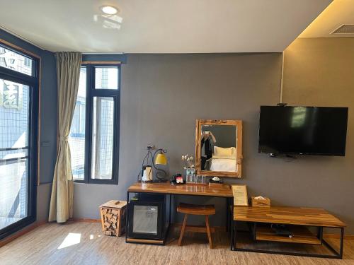 a room with a desk with a mirror and a tv at House of Ahan in Meishan