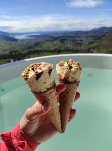 a person holding up two ice cream cones at Ferienhaus Bergträumli Keine Zufahrt in Gommiswald