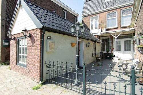 a fence in front of a house with a patio at Cozy tiny house in Halfweg