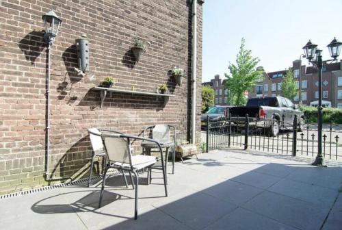 a patio with two chairs and a wrought iron fence at Cozy tiny house in Halfweg