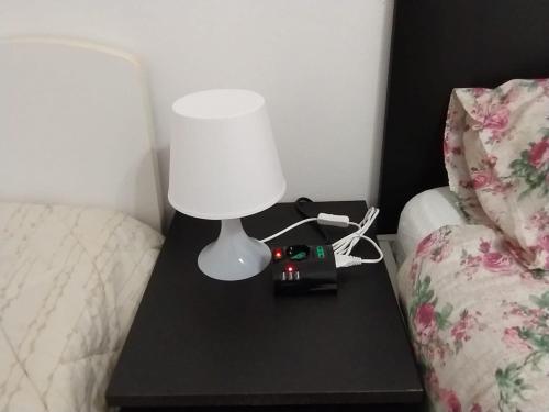 a lamp on a table next to a bed at Sweet home in Somma Lombardo