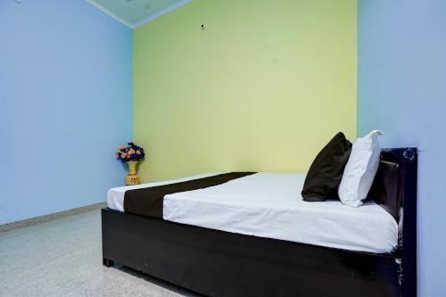 1 dormitorio con 1 cama con sábanas y almohadas blancas en SPOT ON guest house en Bulandshahr