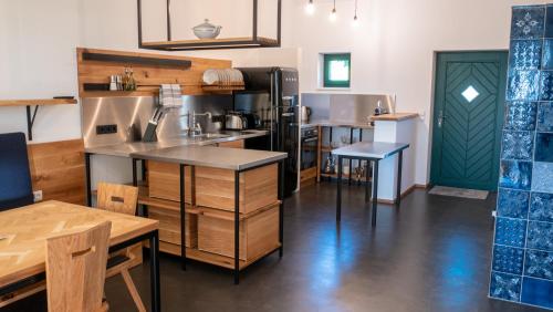 a kitchen with a counter and tables and a green door at Kellerstöckl am Berg in Eisenberg an der Pinka