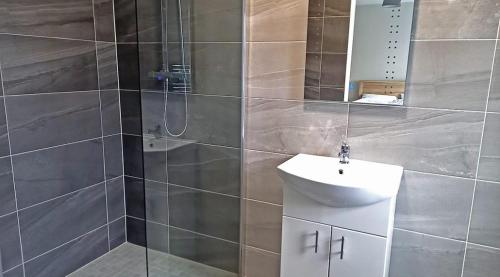 ein Bad mit einem Waschbecken und einer Dusche mit einem Spiegel in der Unterkunft M033 Achill Gatehouse By The Greenway in Westport