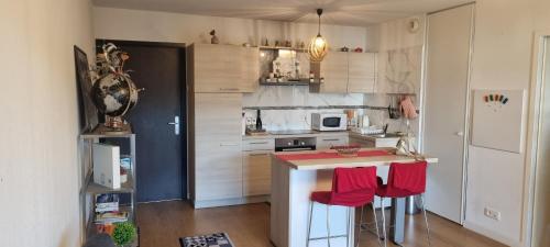 eine kleine Küche mit einer Theke und roten Stühlen in der Unterkunft Appartement Ajaccio in Ajaccio