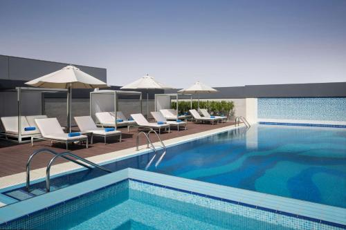 a swimming pool with lounge chairs and umbrellas at Hyatt Place Riyadh Sulaimania in Riyadh