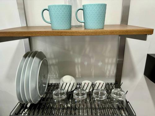 a shelf with cups and wine glasses on a stove at Casa Mira Guadalupe by Leera's Condo in Cebu City
