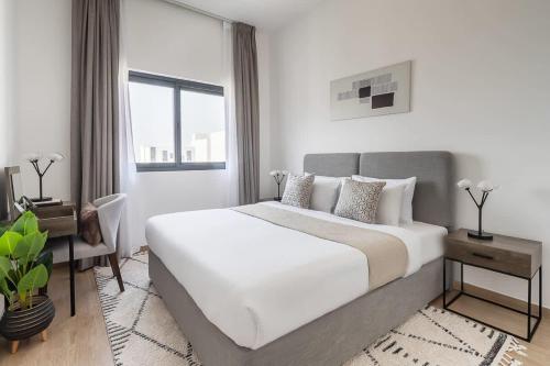a white bedroom with a large bed and a desk at Frank Porter - The Nook 2 in Dubai