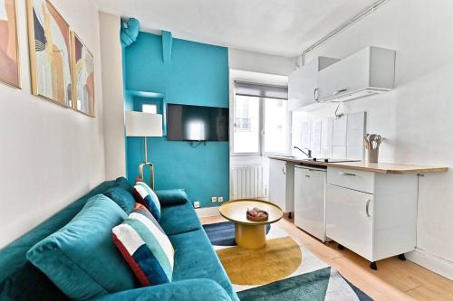 un salon avec un canapé bleu et une cuisine dans l'établissement Appartement coloré Paris Rue Niépce, à Paris
