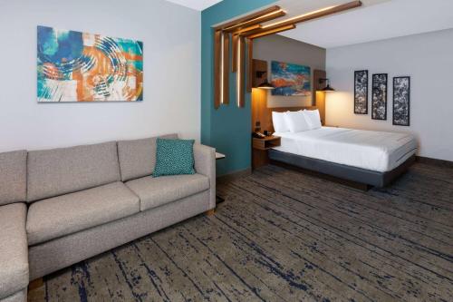 a hotel room with a couch and a bed at La Quinta Inn & Suites by Wyndham Dallas - Frisco Stadium in Frisco