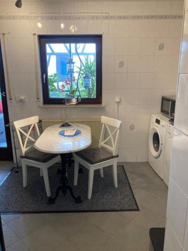 a kitchen with a table and two chairs and a washing machine at Apartment mit Wintergarten und Terrasse in ruhiger Lage im schönen Taunus in Glashütten