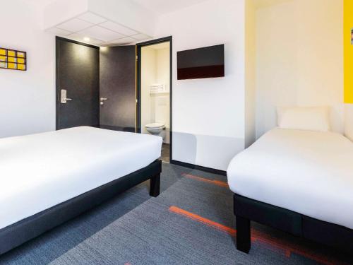 Cette chambre comprend 2 lits et une télévision. dans l'établissement greet Hotel Nancy Sud, à Houdemont