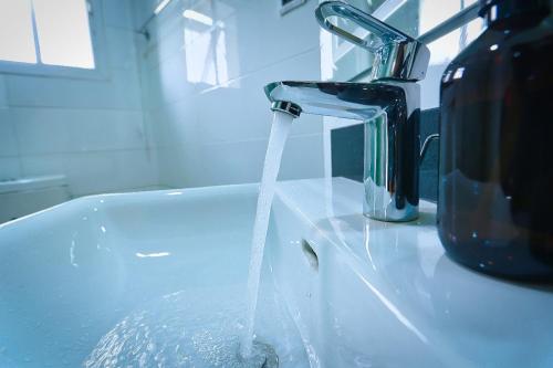 a bathroom sink with water running from a faucet at Hamasvile Hotel Utako Abuja in Abuja