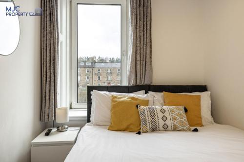 a bedroom with a bed with yellow pillows and a window at Riverside in Hawick
