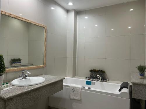 y baño con lavabo, bañera y espejo. en Subic Residencias, en Olóngapo