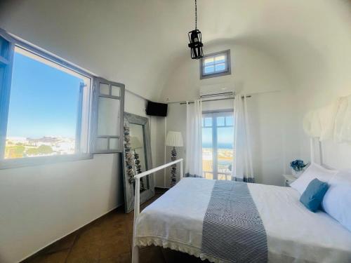 a white bedroom with a bed and a large window at Santorini Mesotopos in Fira
