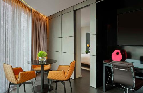 una habitación con mesa y sillas y un dormitorio en art'otel London Hoxton, Powered by Radisson Hotels, en Londres