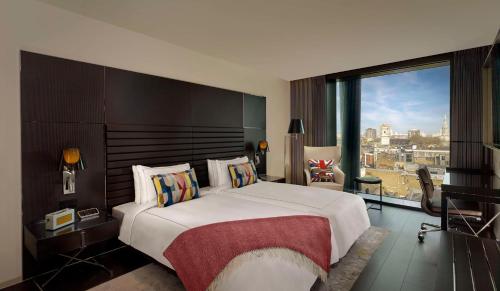 a bedroom with a large bed and a large window at art'otel London Hoxton, Powered by Radisson Hotels in London