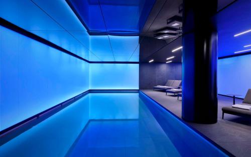 a swimming pool in a room with blue lighting at art'otel London Hoxton in London
