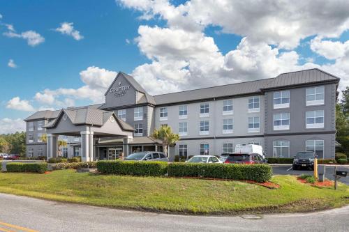 ein großes Gebäude mit Autos auf einem Parkplatz in der Unterkunft Country Inn & Suites By Radisson, Savannah Airport, GA in Savannah