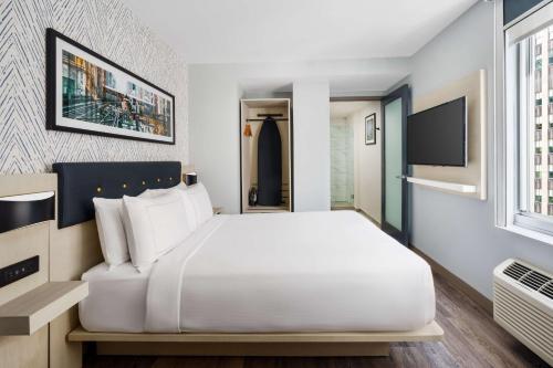 a bedroom with a large white bed and a tv at DoubleTree by Hilton New York Midtown Fifth Ave in New York