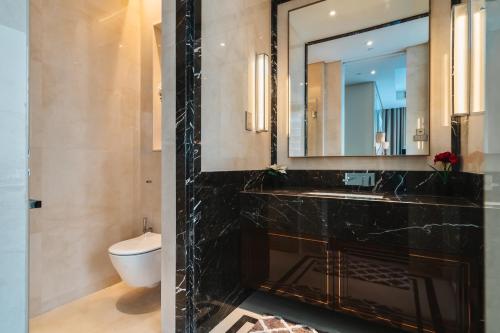 a bathroom with a sink and a toilet and a mirror at Luxury 2BR Designer Suite above Pavilion Mall in Kuala Lumpur