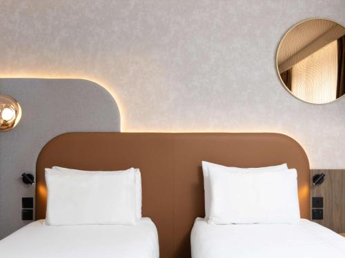 two beds in a hotel room with a mirror at Mercure London Earls Court in London