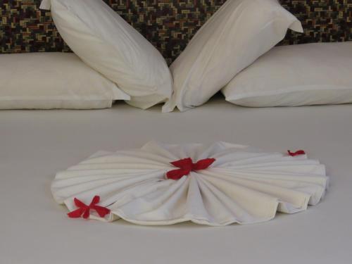 a bed with white pillows with red bows on it at Golden Hill Parker Hotel in Elmina