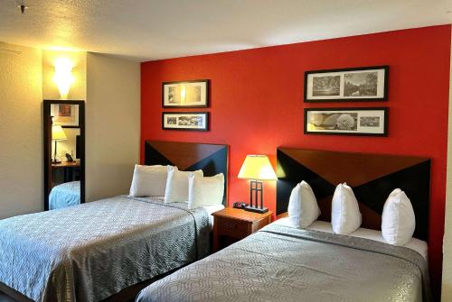 2 łóżka w pokoju hotelowym z czerwonymi ścianami w obiekcie Howard Johnson by Wyndham Urbana w mieście Champaign