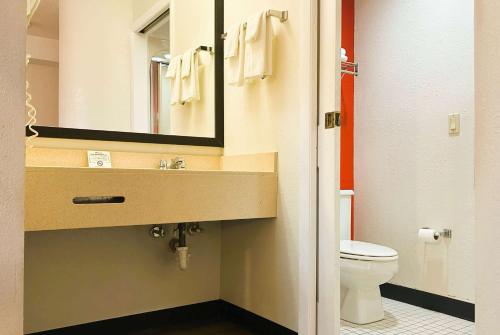 a bathroom with a sink and a toilet and a mirror at Howard Johnson by Wyndham Urbana in Champaign