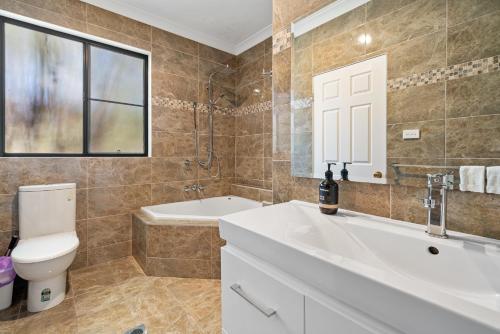 a bathroom with a toilet and a sink and a tub at Perfectly Located Complete Villa in Pokolbin