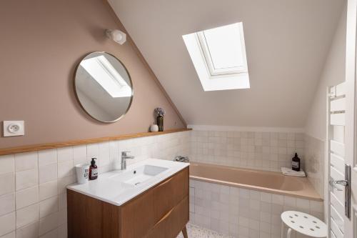 W łazience znajduje się umywalka, wanna i lustro. w obiekcie La Buissonnière - Maison à 5 min des plages w mieście Le Minihic-sur-Rance
