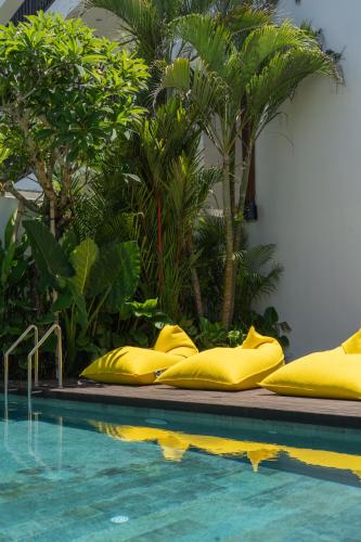 a swimming pool with yellow pillows next to a resort at Sunny Cuddles in Canggu