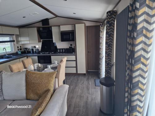 a living room with a table and chairs and a kitchen at Beachwood 21 in Camber