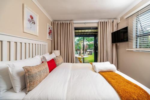 1 dormitorio con 1 cama blanca grande y TV en Kamuzi exquisite tiny home near airport - 2217 en Harare
