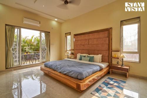 a bedroom with a large bed and a balcony at StayVista's Tableland Vista - Hill-View Haven with Jacuzzi & Terrace in Panchgani