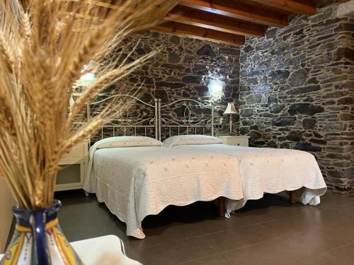 a bedroom with a bed in a stone wall at Adega in Ordes